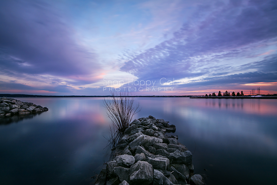 Photo: Rocky breakwalls jut into the smooth waters of West Traverse Bay at sunset